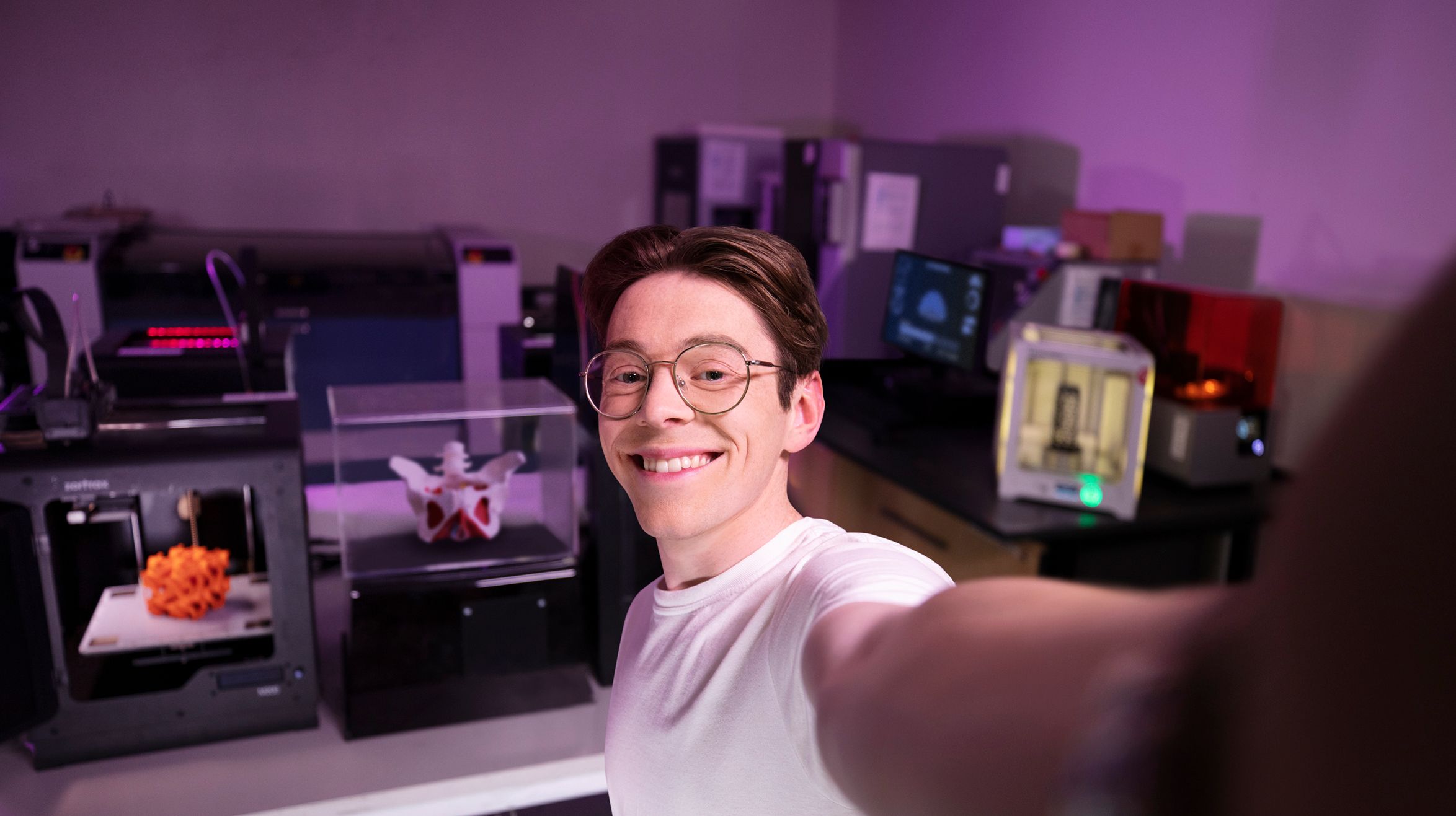 Joshua selfie style photo in science Lab Male student smiling at the camera taking a selfie style photo, in the background shows a dimly lit science lab.