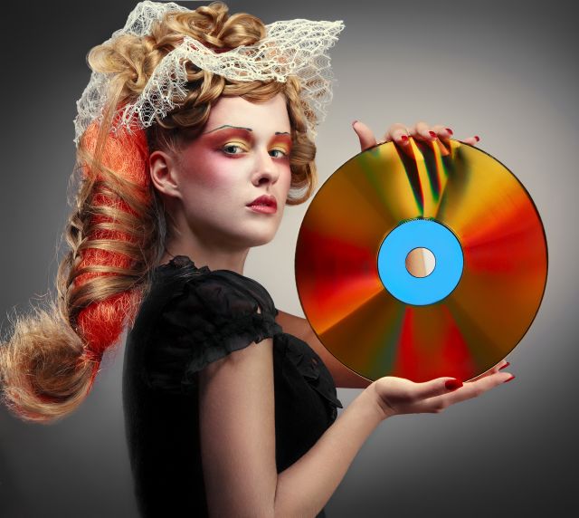 Woman with exaggerated makeup and lace in her hair holding up a laser disc Woman with exaggerated makeup and lace in her hair holding up a laser disc