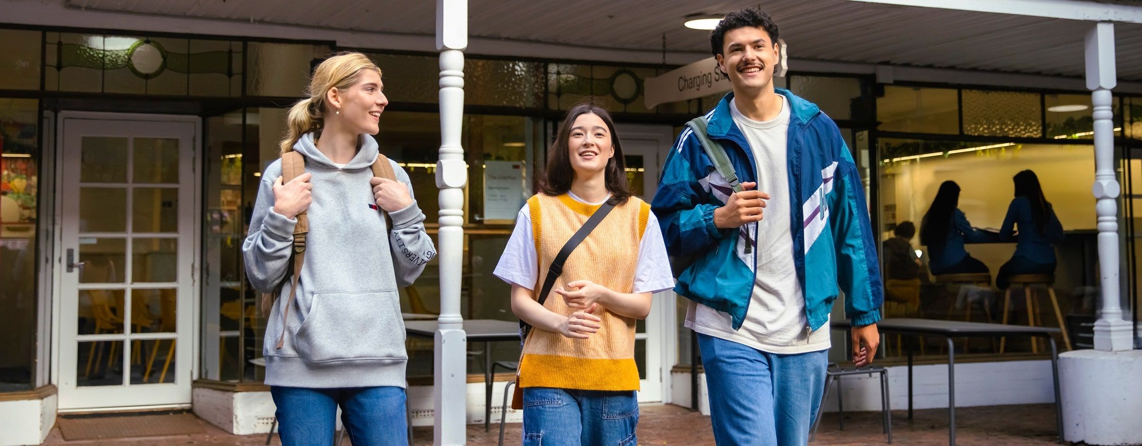 Train station graphic Three students walking and chatting outside a campus building, with a timeline graphic below showing steps from “Ready for Change” to “Unlock Your Ambitions.”