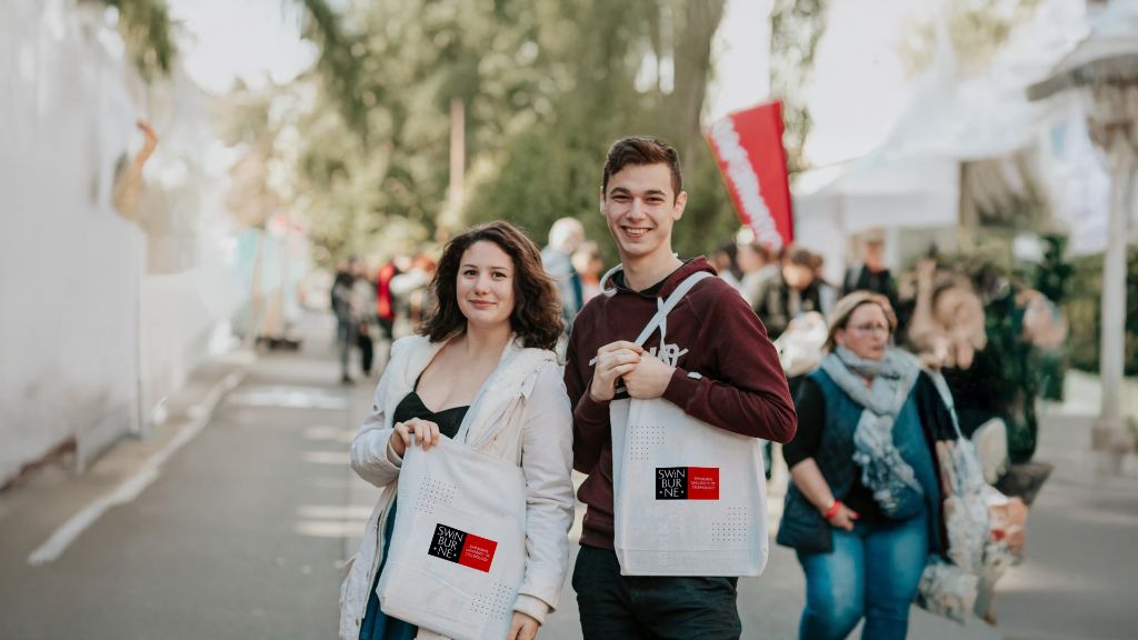 Two people standing with tote bags smiling at the camera