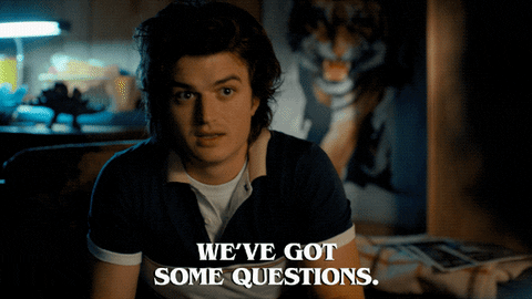 Two young men exchange words in a bedroom with a white caption that reads 'We've got some questions. Lots of questions.'