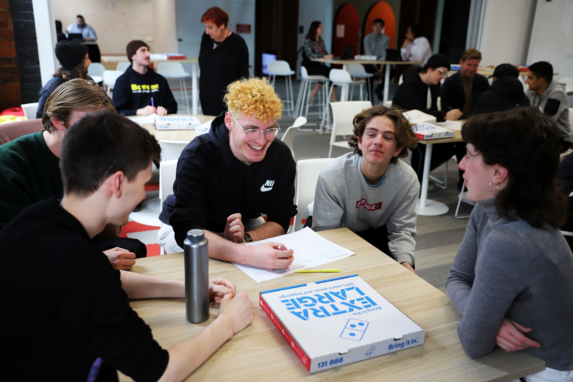 Students gather around toables and have a discussion