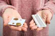 Woman holding in hands oral contraceptive pills and condom, choice. Concept gynecology, sex education.