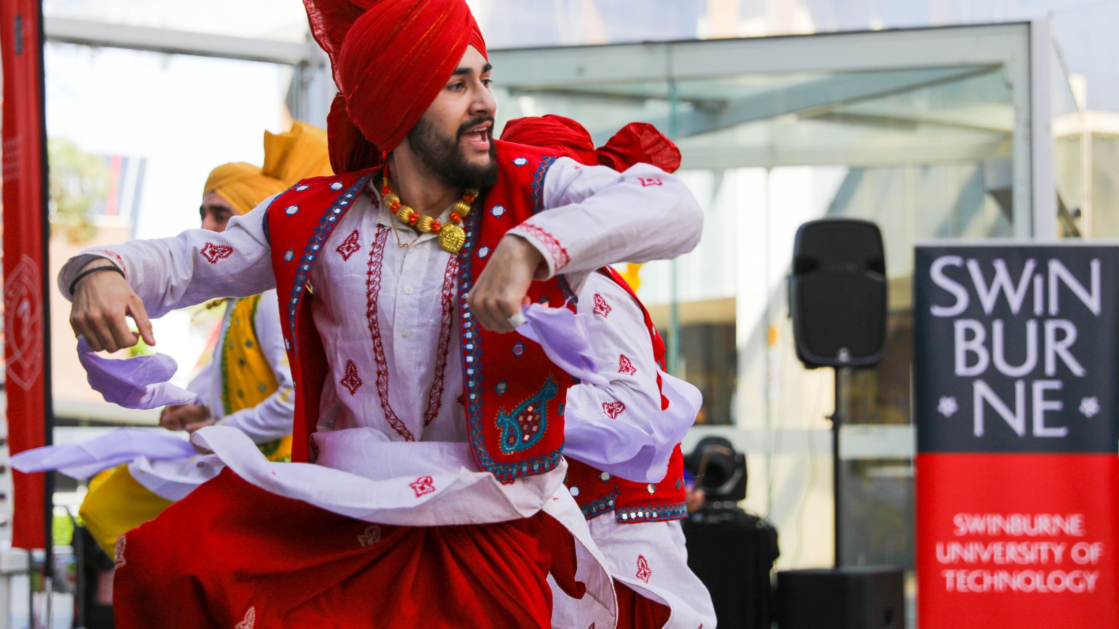 Diwali, 2017 Man wearing bright red traditional Diawli attire dances upon a Swinburne stage