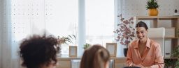 Woman smiling as she speaks with two children in a bright office