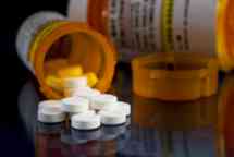  Prescription bottle of white Oxycodone tablets and pills spilt out on glass table with reflections