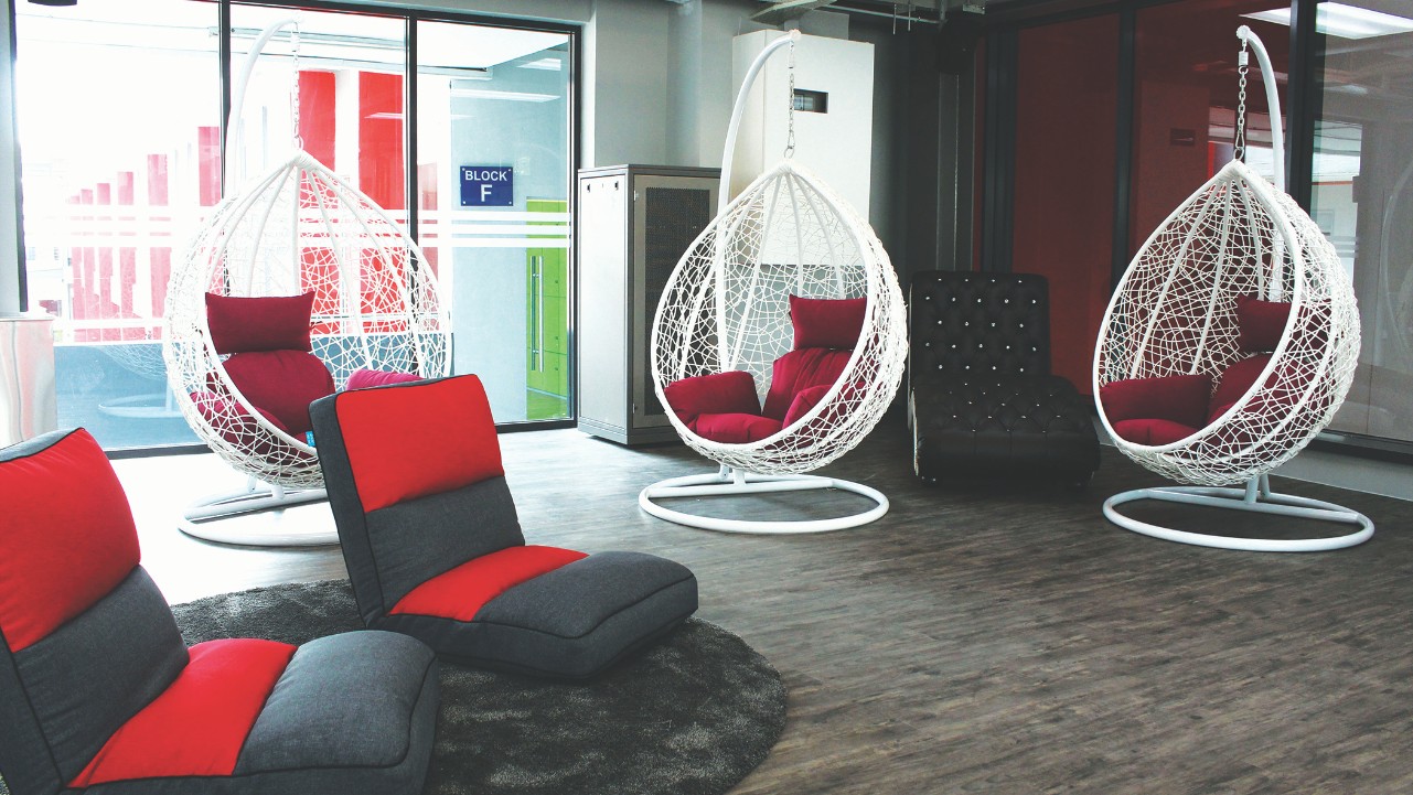 Hanging chairs and couches for relaxing in a cozy red and grey room.