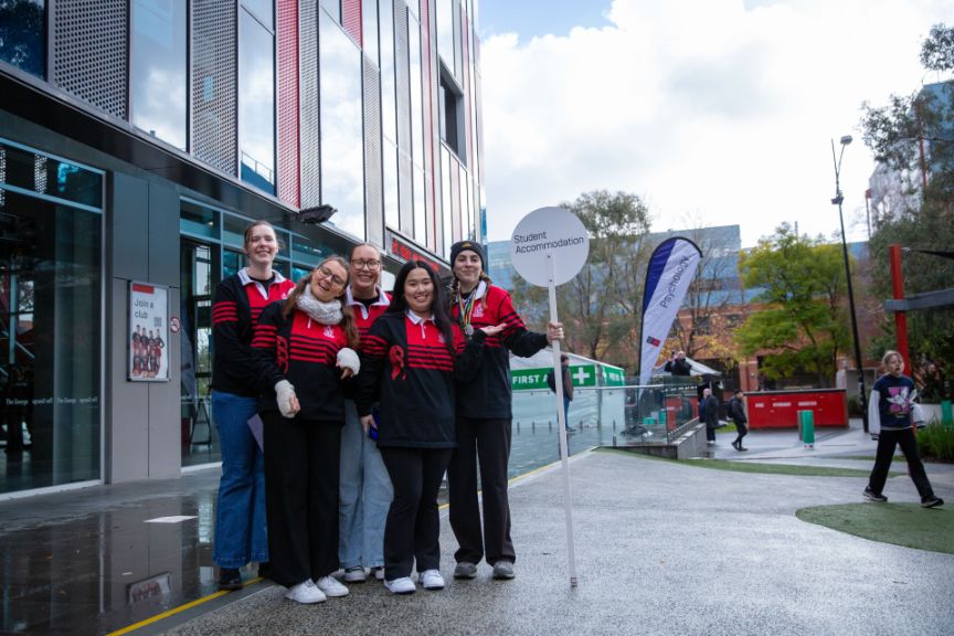 A group of people standing outside with a sign