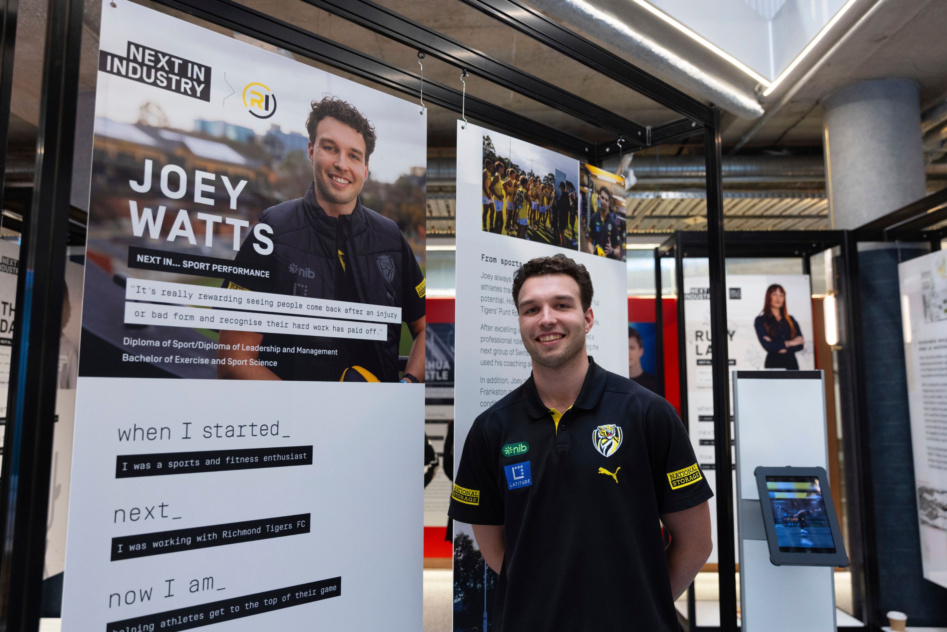 A student stands next to a poster about his Work Integrated Learning experience, featuring his photo and story.