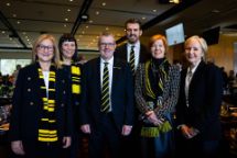 6 professional people at a football game wearing Richmond Football Club scarves. 