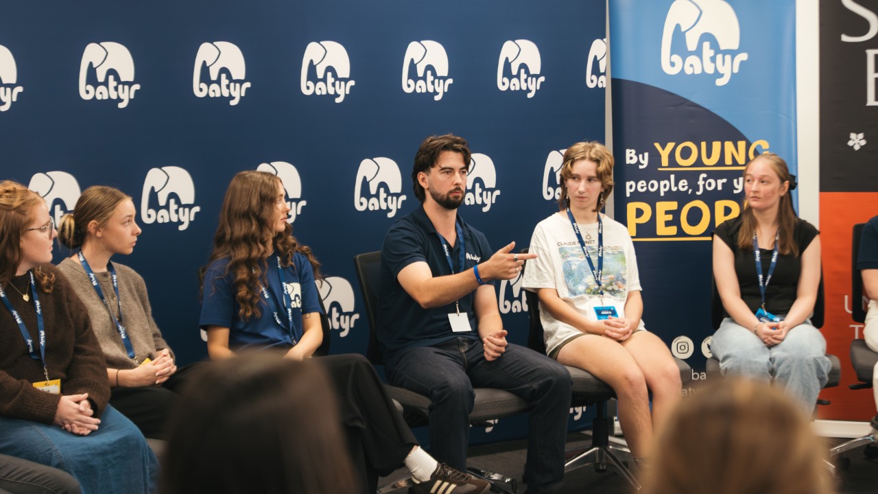 A batyr panel discussion with students and speakers seated on stage in front of batyr banners.