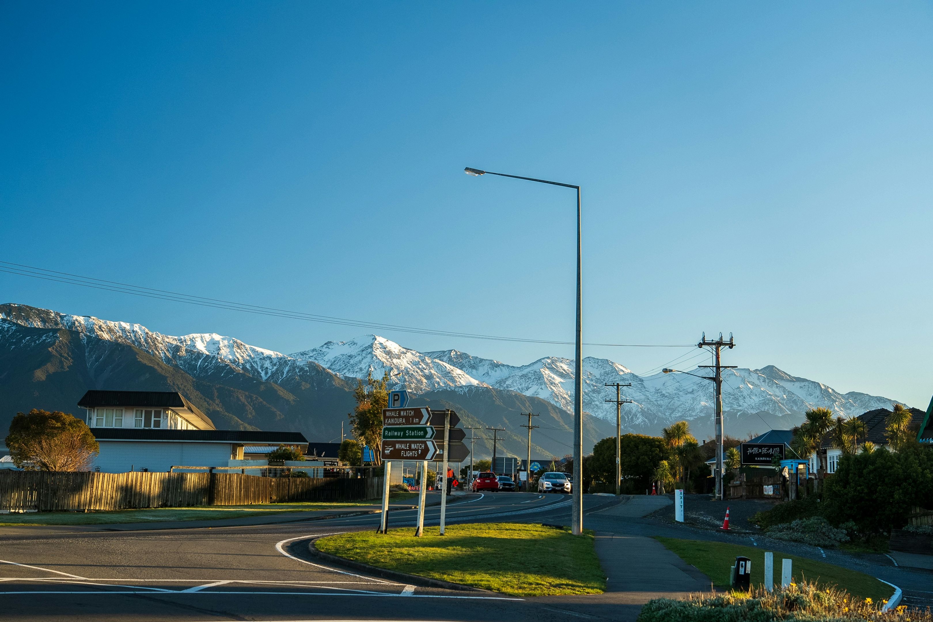 Scenic view of a road in a small town with snow capped mountains behind