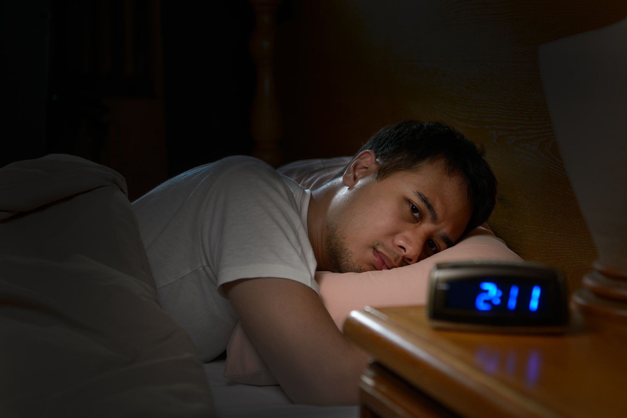 Young man having trouble getting to sleep. Depressed man suffering from insomnia lying in bed