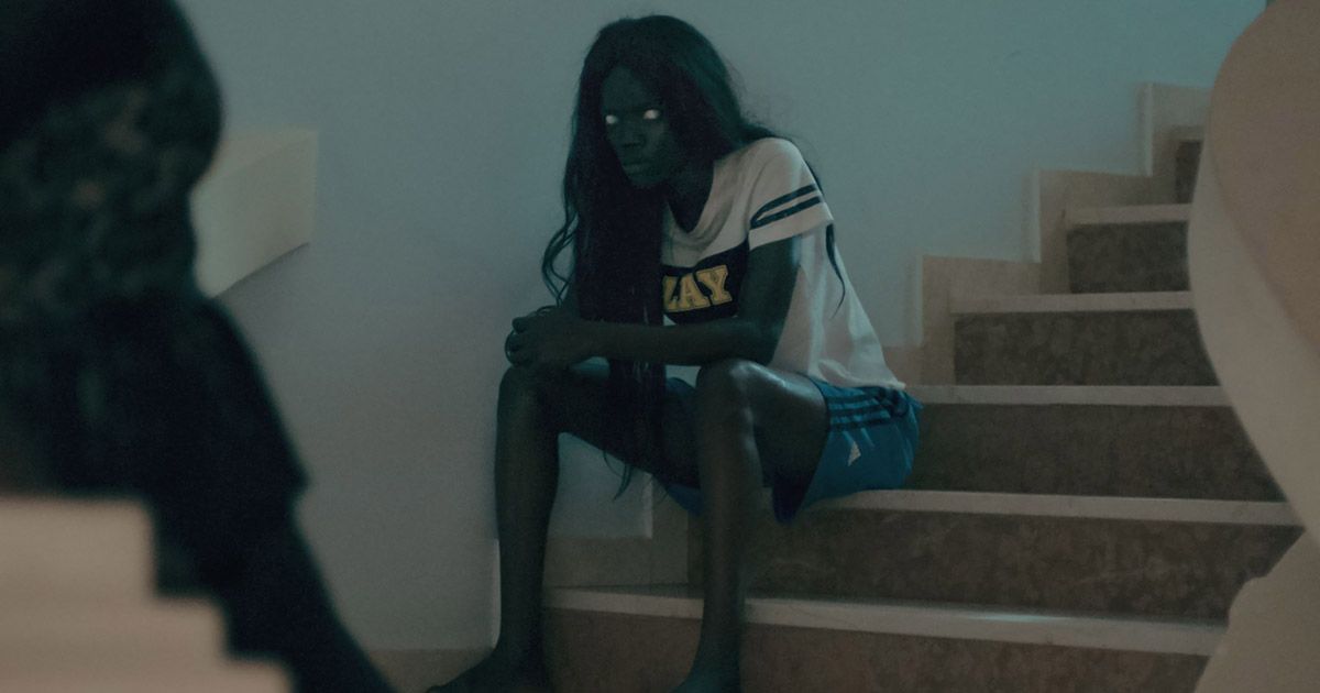 Atlantics Women from Atlantics with white eyes, black hair, sitting on the bottom of stairs.