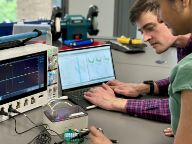 A man and woman look over computer data and tinker with electronics
