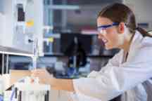 bio student in lab coat wearing safety glasses works in the laboratory