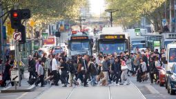 Pedestrians and trams at a busy intersection in Melbourne