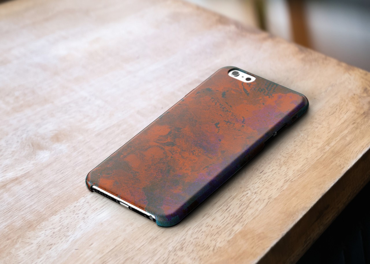 A mockup of a copper phone case sitting on a wooden table, very heavy wear and darkening