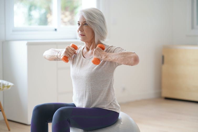 Exercising in the winter Women sitting on an exercise ball as she lifts dumbells