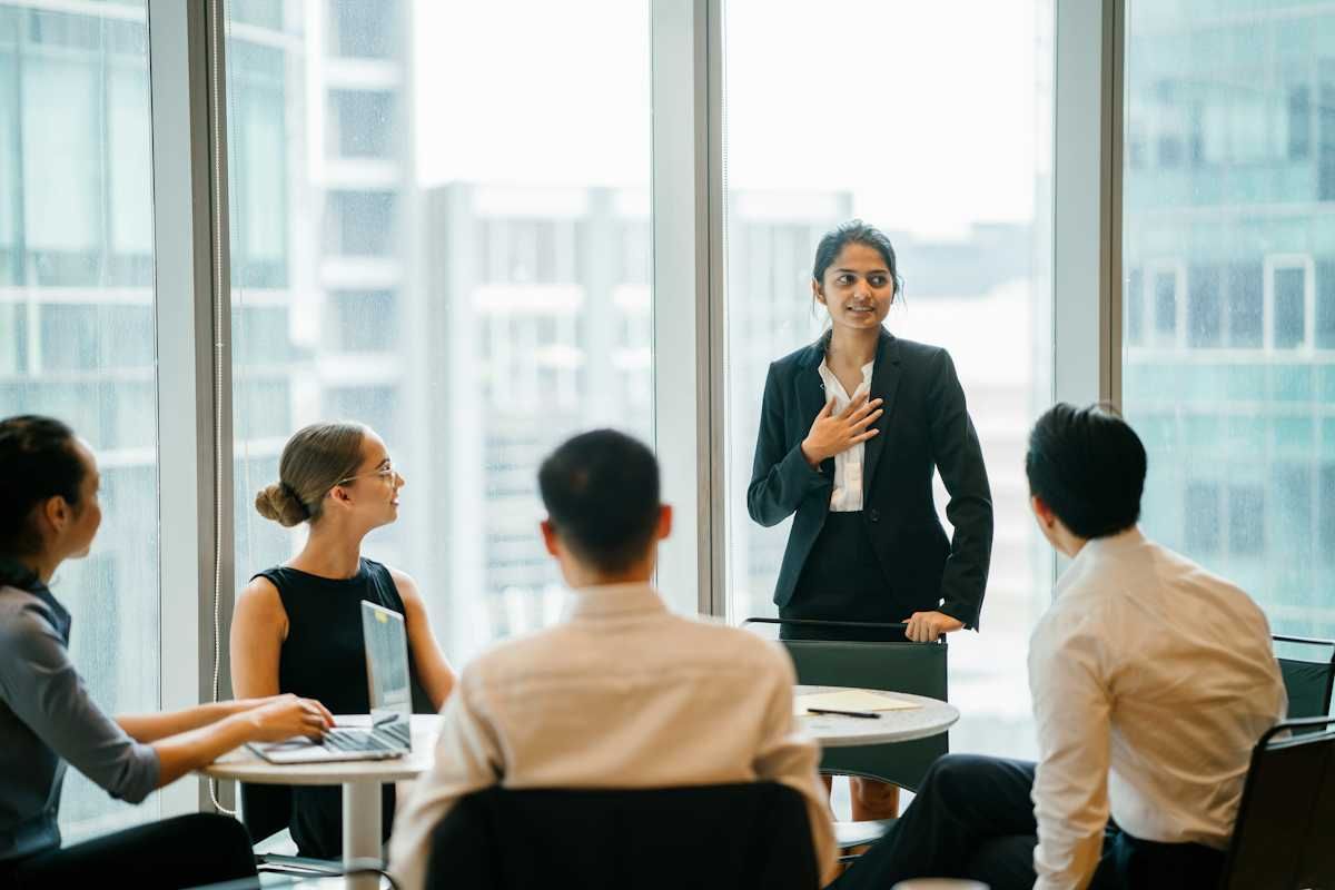 Framing weaknesses in a job interview Women speaking at a business meeting with four people listening