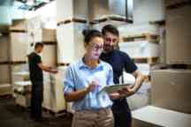 Warehouse worker and supervisor looking at a tablet computer.