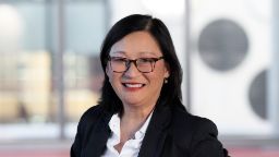 Lady with long back hair with glasses, black jacket, white shirt