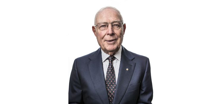 Professor Murray Gillin AM An older man dressed in a suit smiles at the camera in front of a white background