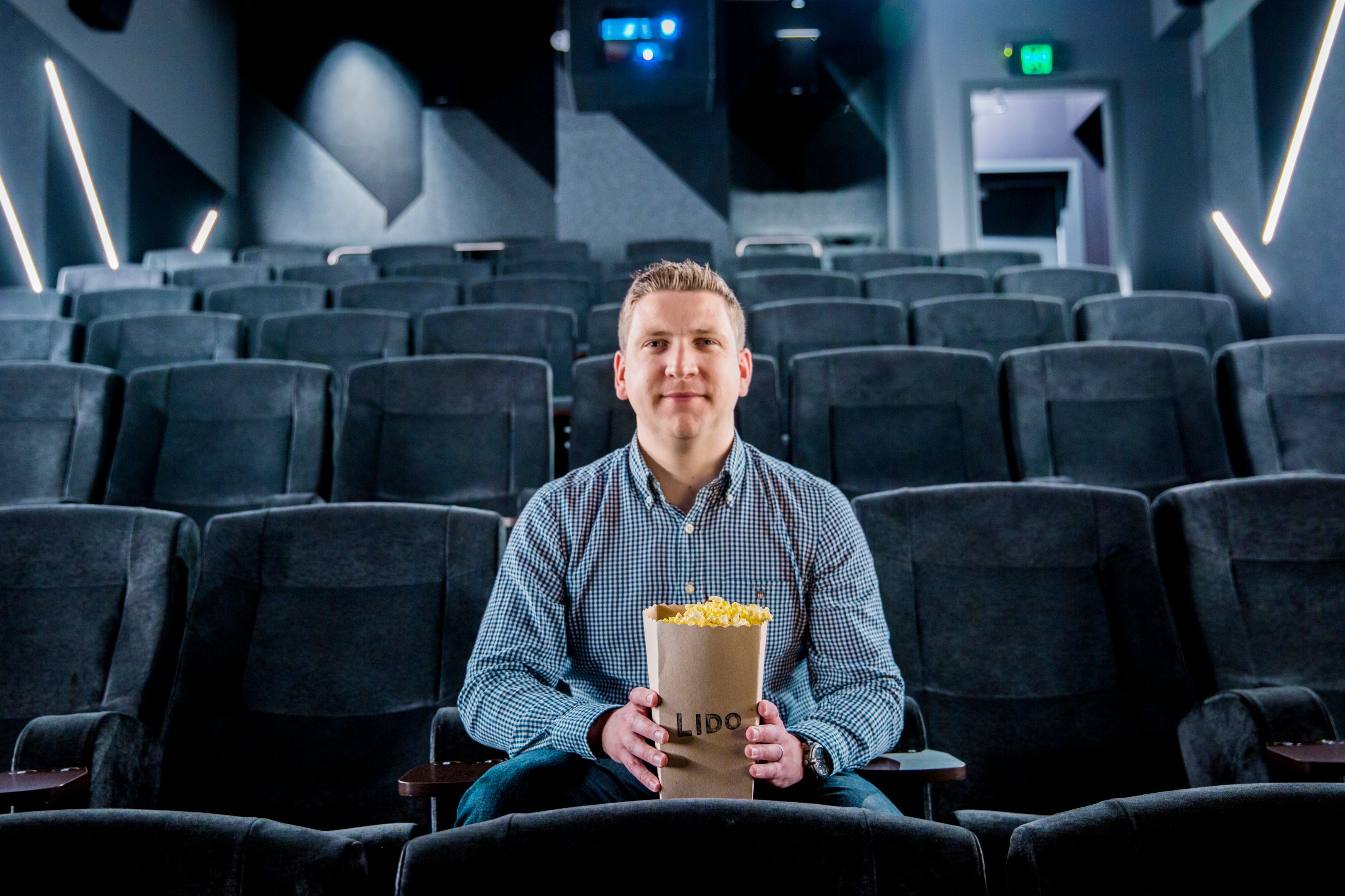 Liam Burke at the cinema Young man sits in an empty cinema with a bucket of Lido popcorn.