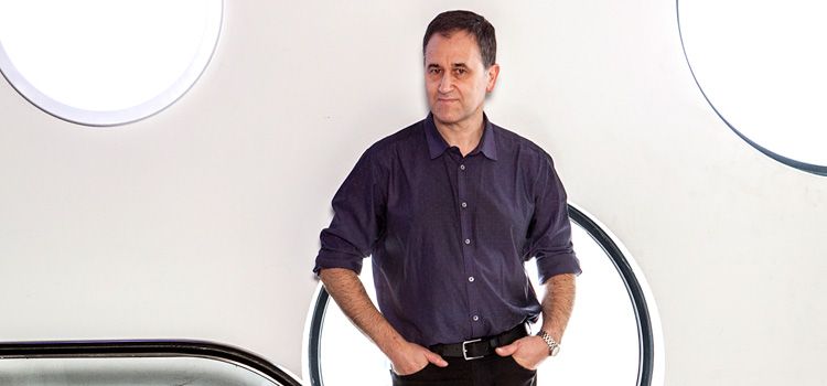 Professor Enzo Palombo A man dressed in business casual clothes stands in front of a wall covered in large, circular windows