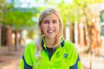 Female student wearing high vis jacket studying plumbing smiles to camera
