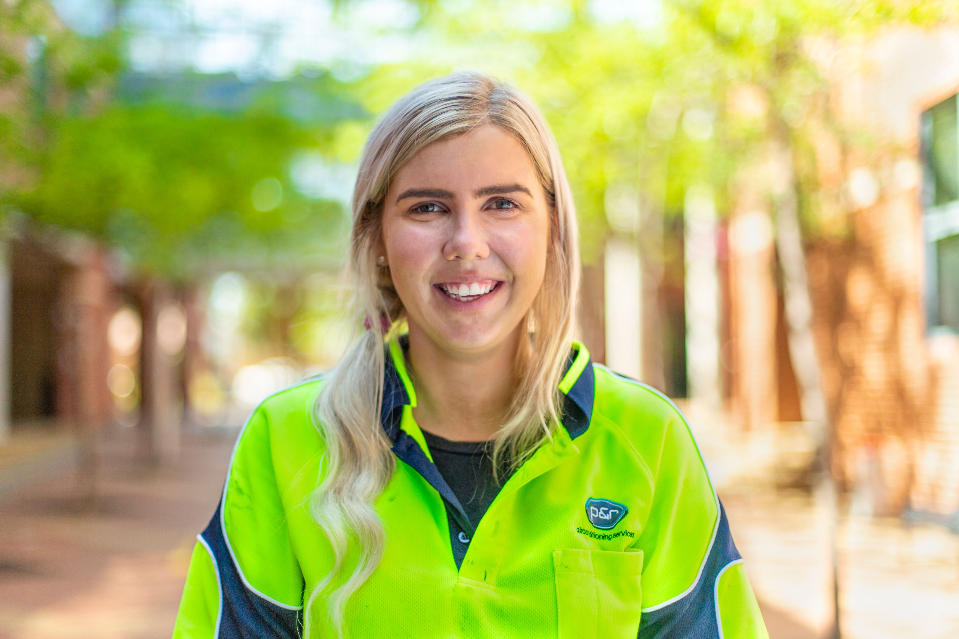 Aimee Stanton Female student wearing high vis jacket studying plumbing smiles to camera
