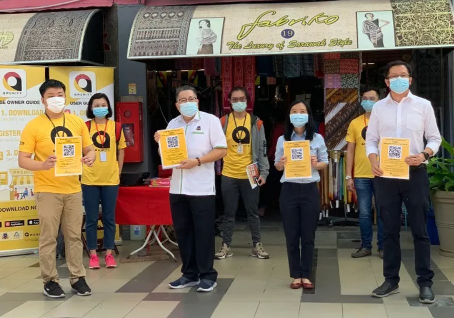 COVID app Qmunity in Sarawak Sarawak community holding QR code for Qmunity COVID-19 tracking app