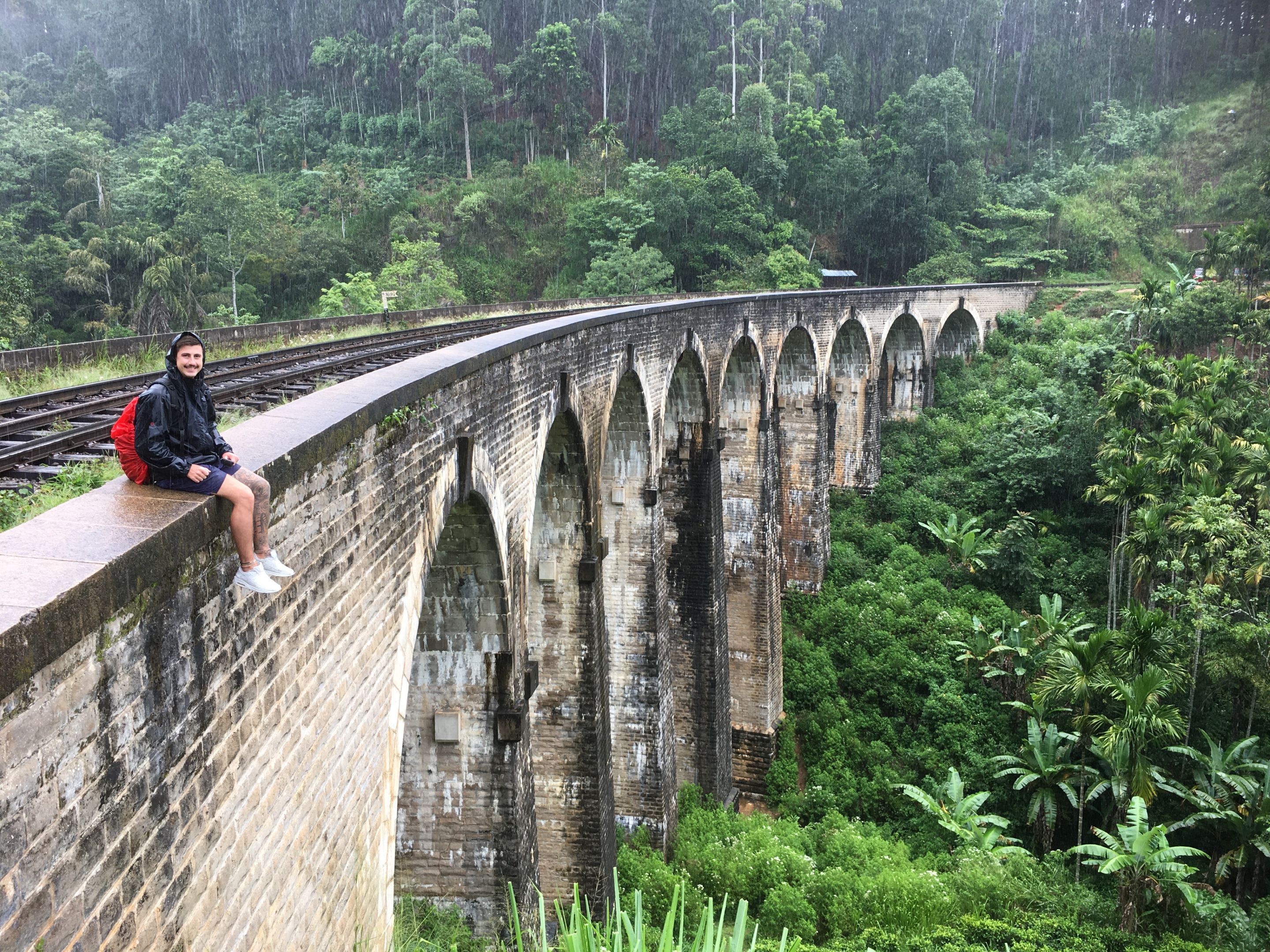 Study abroad and exchange student Brayden Man sitting on a old train bridge with a forest in the background