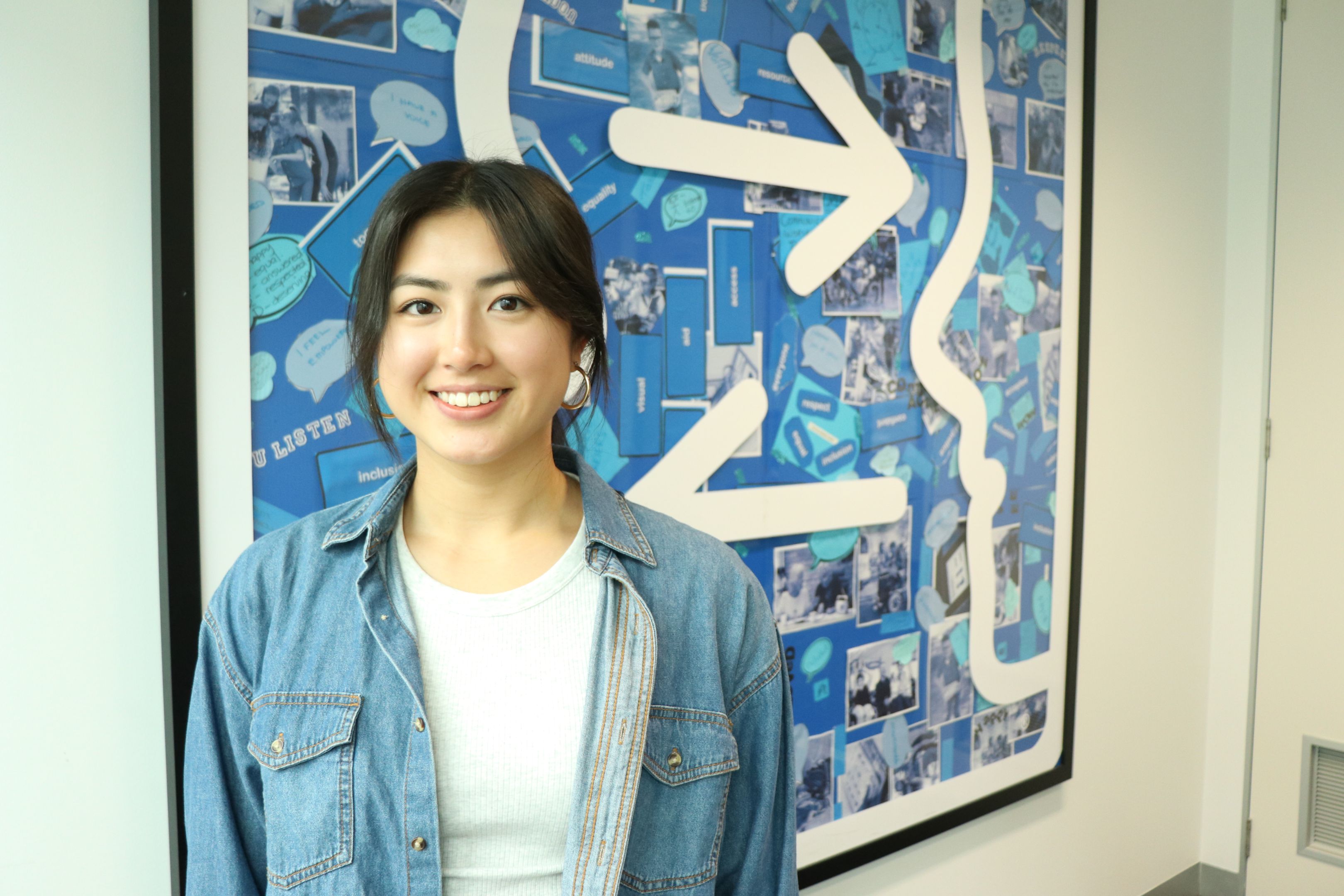 Elysia Yong Swinburne professional placement student, Elysia, standing in front of a blue abstract artwork.