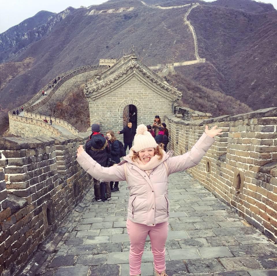 Study abroad and exchange student Emily Female student in pink smiling at the camera while on the Great Wall of China