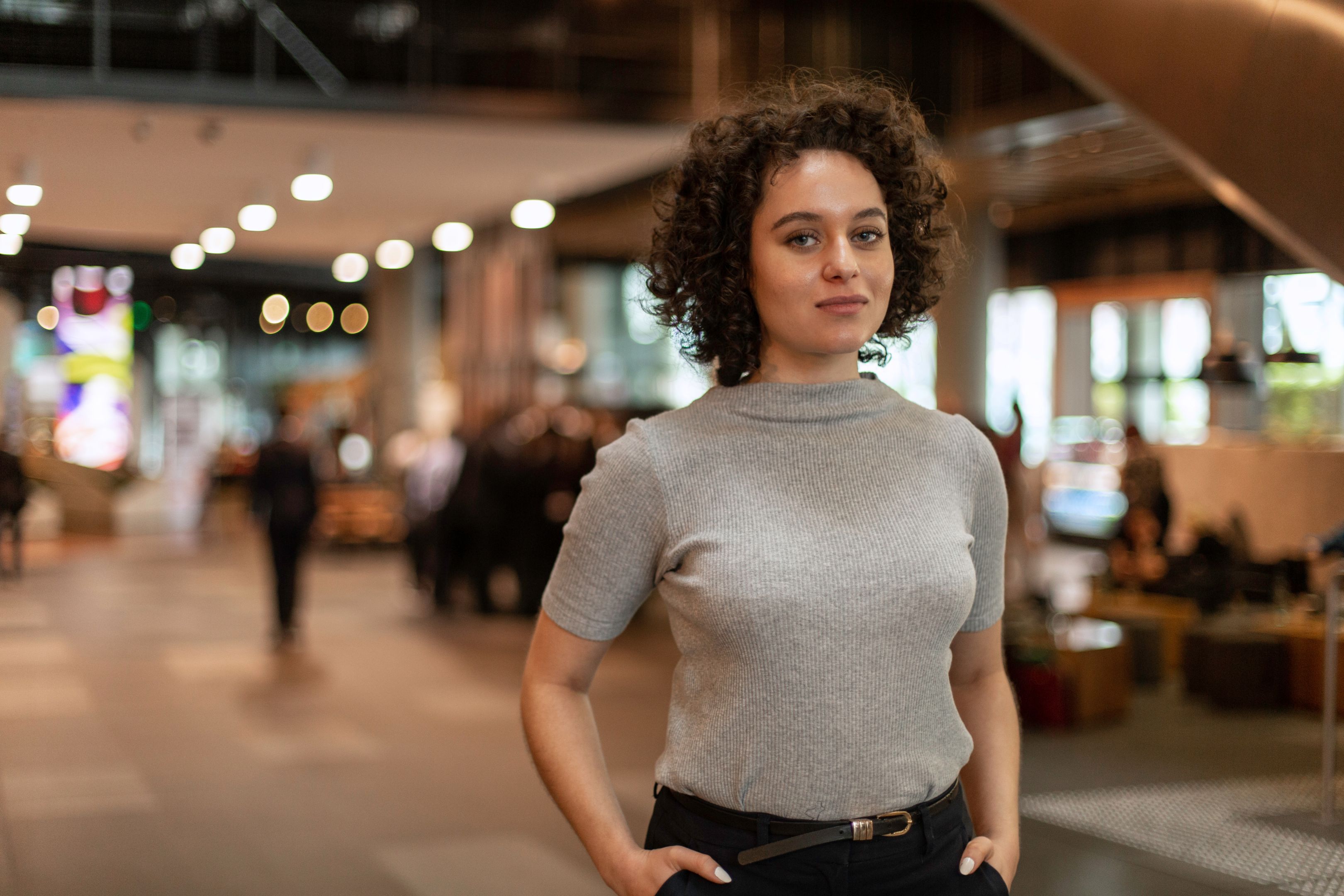 Female student on a professional placement stands in the office and smiles to camera