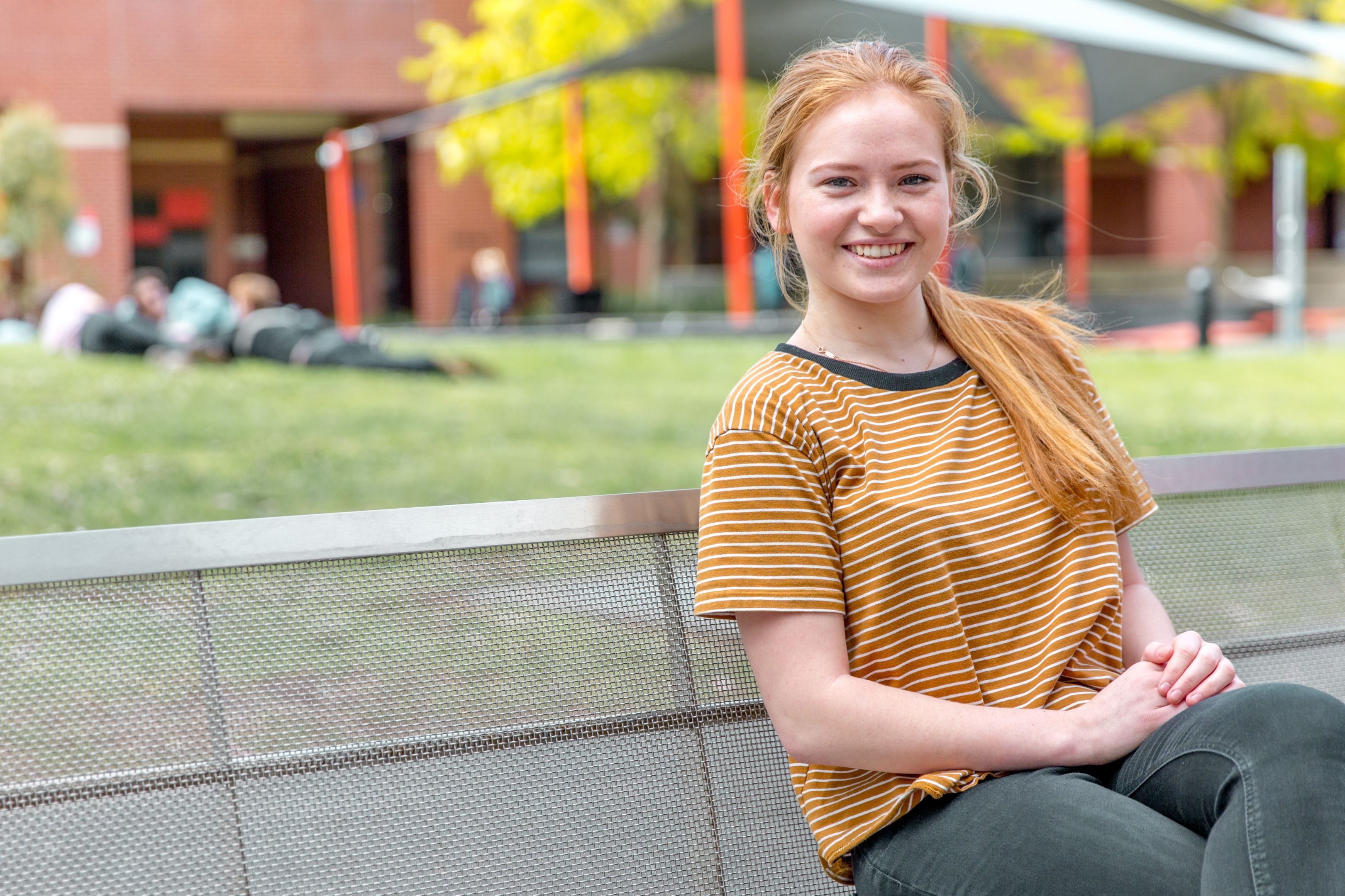 Neane Carter Young woman sits on bench smiling at camera