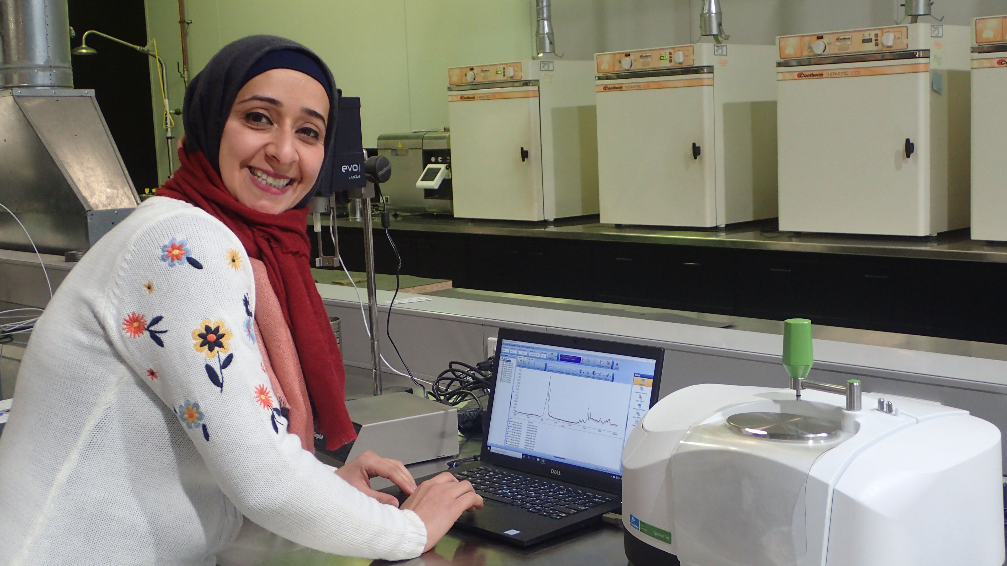 Khulood Hashim Hwayyis PhD student at her internship smiling with her laptop.