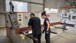 Yu-Ju and a trade student using a machine in a workshop.