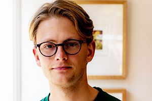 Geordie Launder A man with light brown hair and black glasses looks to camera
