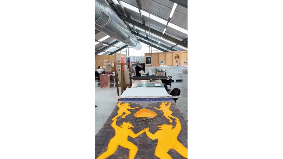 Large-scale student artwork displayed on a worktable in an art and design studio.