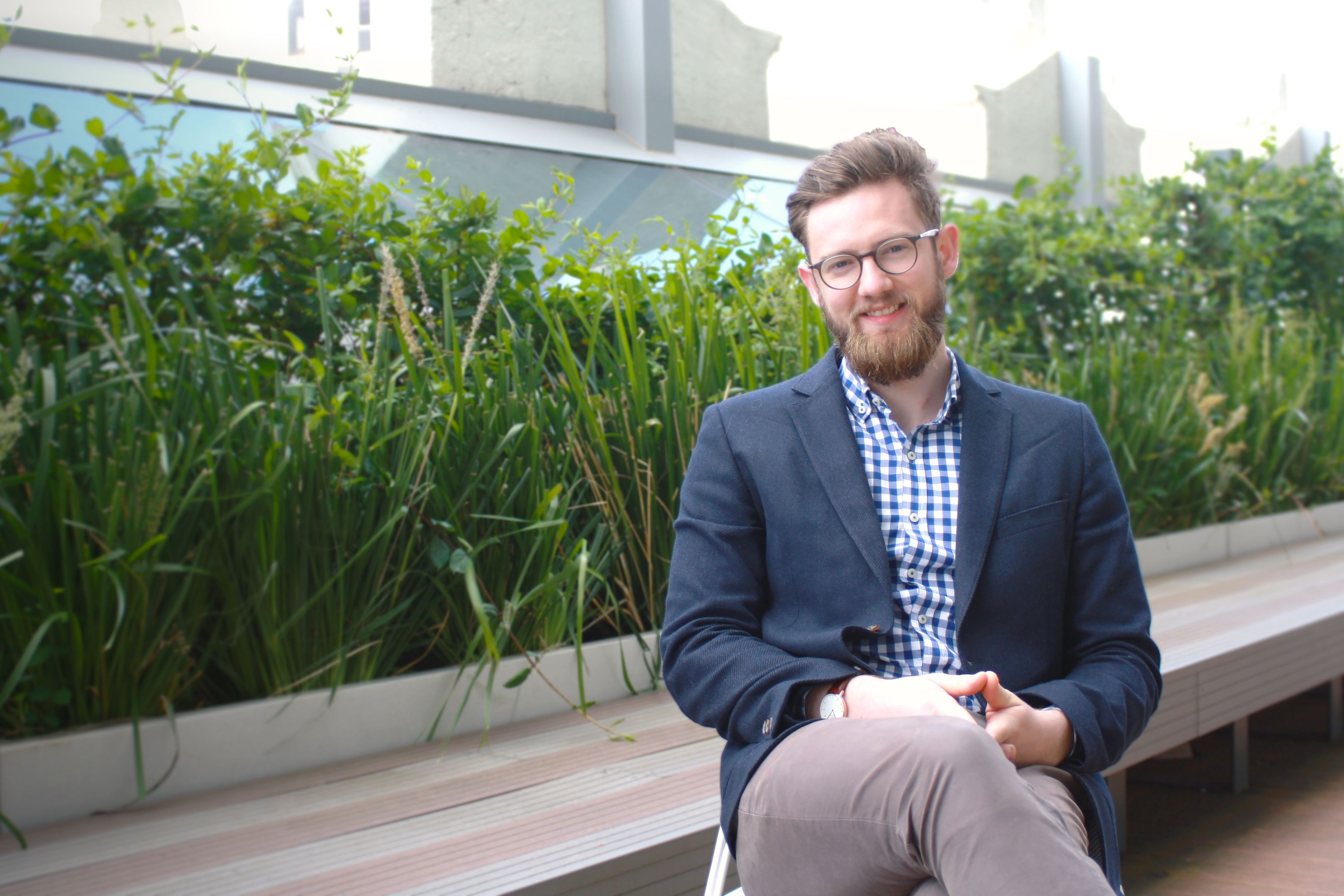James Hanley James Hanely sits relaxed with legs crossed in front of a green garden bed