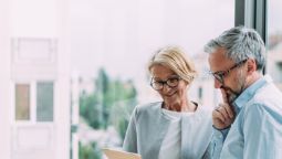 Two older executives in an office reading a document