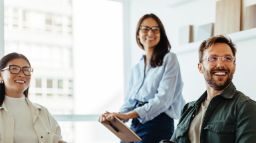 Three young professionals in an office smiling