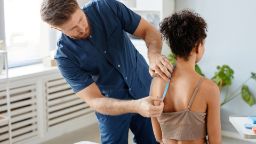 A physiotherapist examining a client's back in a clinic