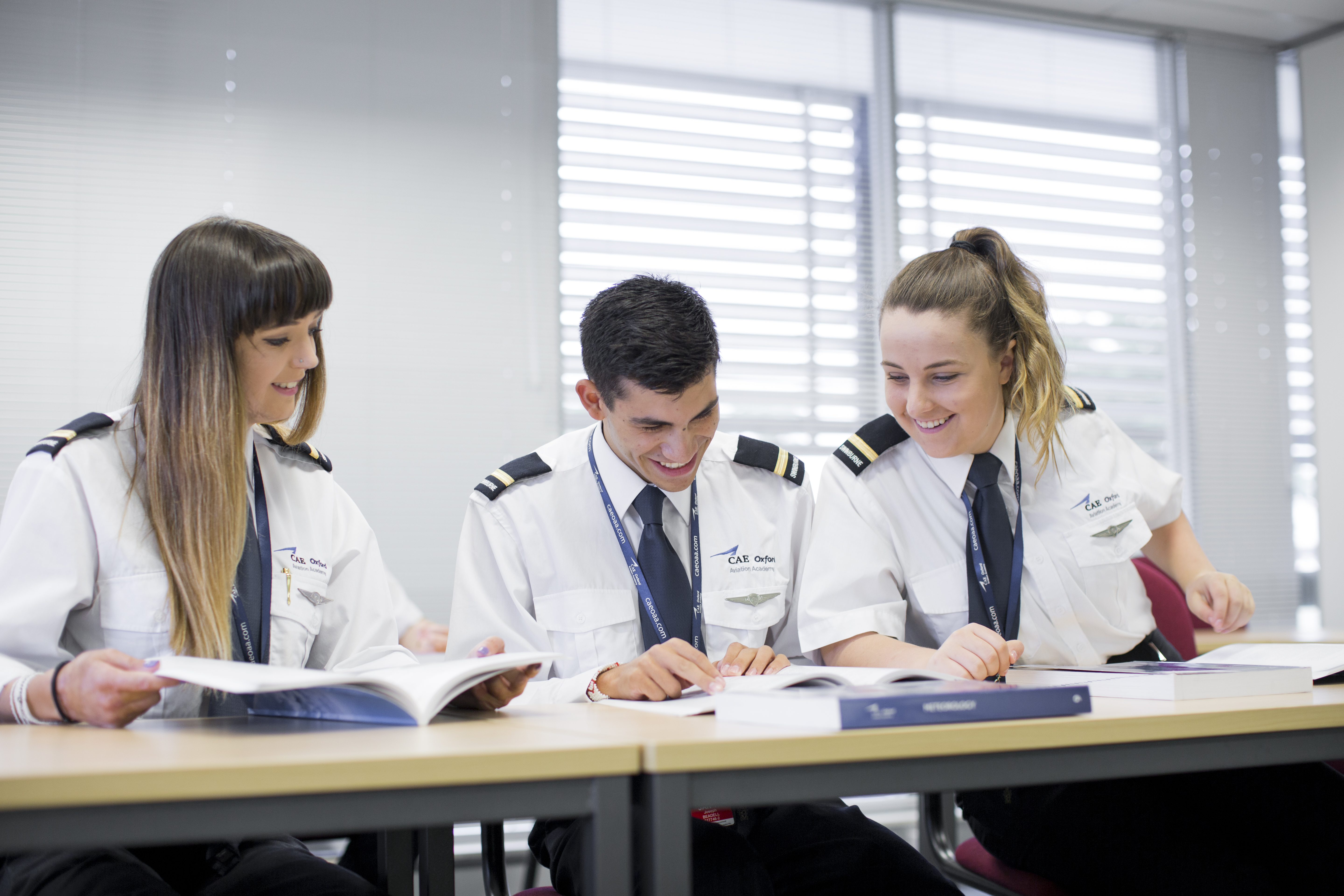 Aviation students chatting as they sit at a desk with their books open 