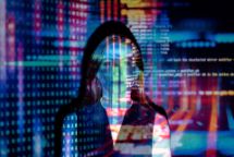 A woman's face is illuminated by a neon digital projection of data 