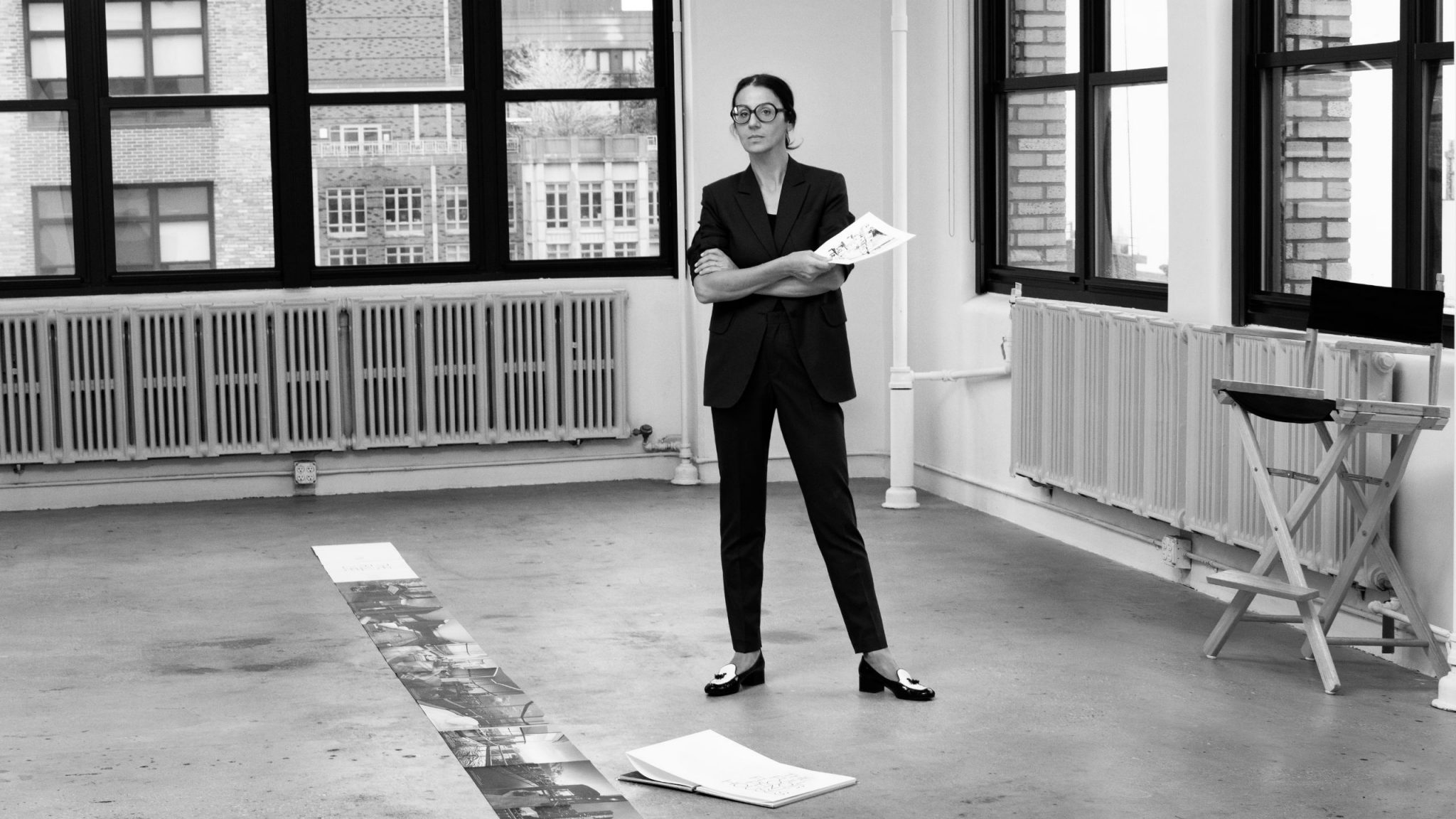 Visnja Brdar in a NYC warehouse A black and white shot of Visnja standing, arms crossed in a cavernous NYC warehouse. She is laying out designs for the Penthouse Book Construction